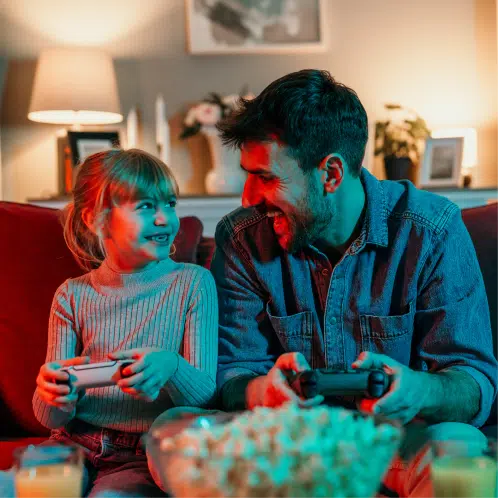 Wie-geht-es-nach-dem-Stromanbieterwechsel-weiter Ein Vater und seine Tochter essen Popcorn, lächeln und schauen einen Film.