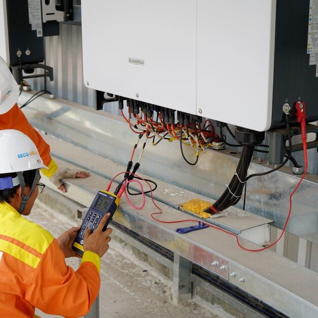 speicher Two electrical engineers installing and testing solar power systems wearing safety gear at a construction site.